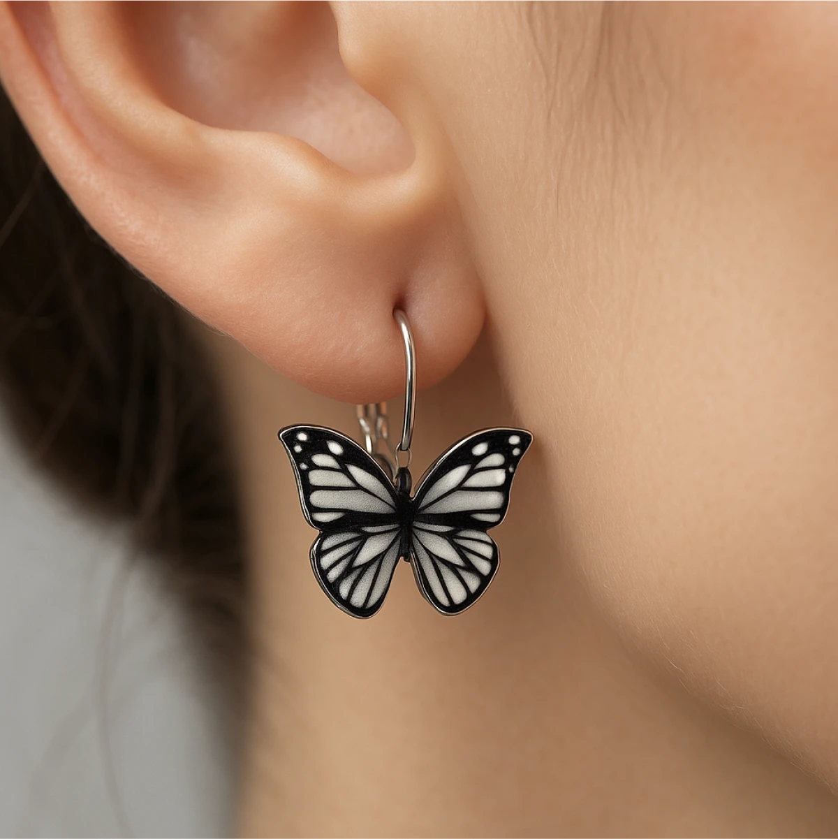 Butterfly-shaped earring worn on an ear with a neutral background