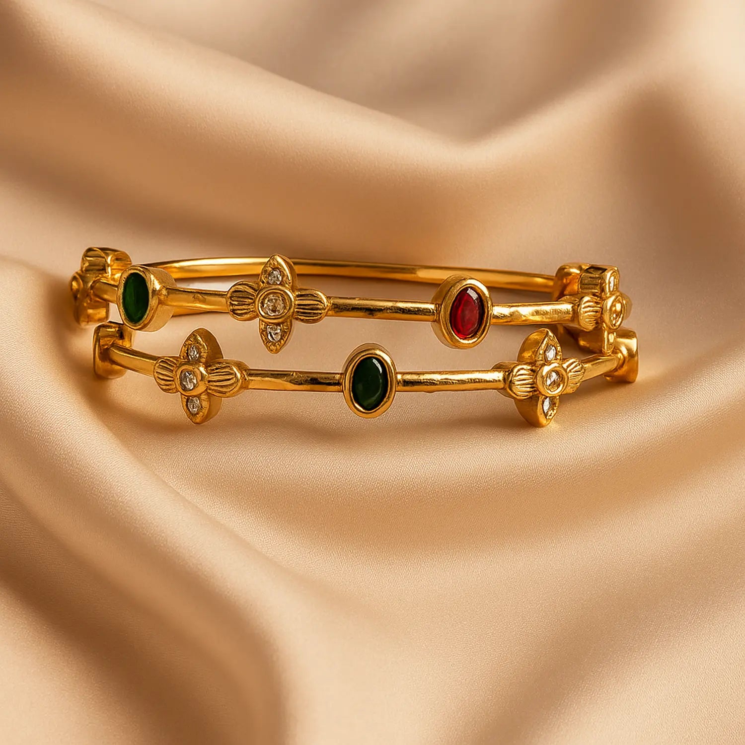 Gold bangles with gemstones on a beige fabric background