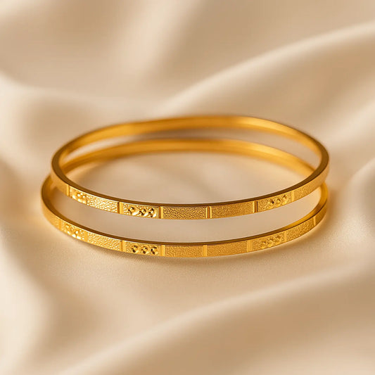 Two gold bangles on a beige satin background