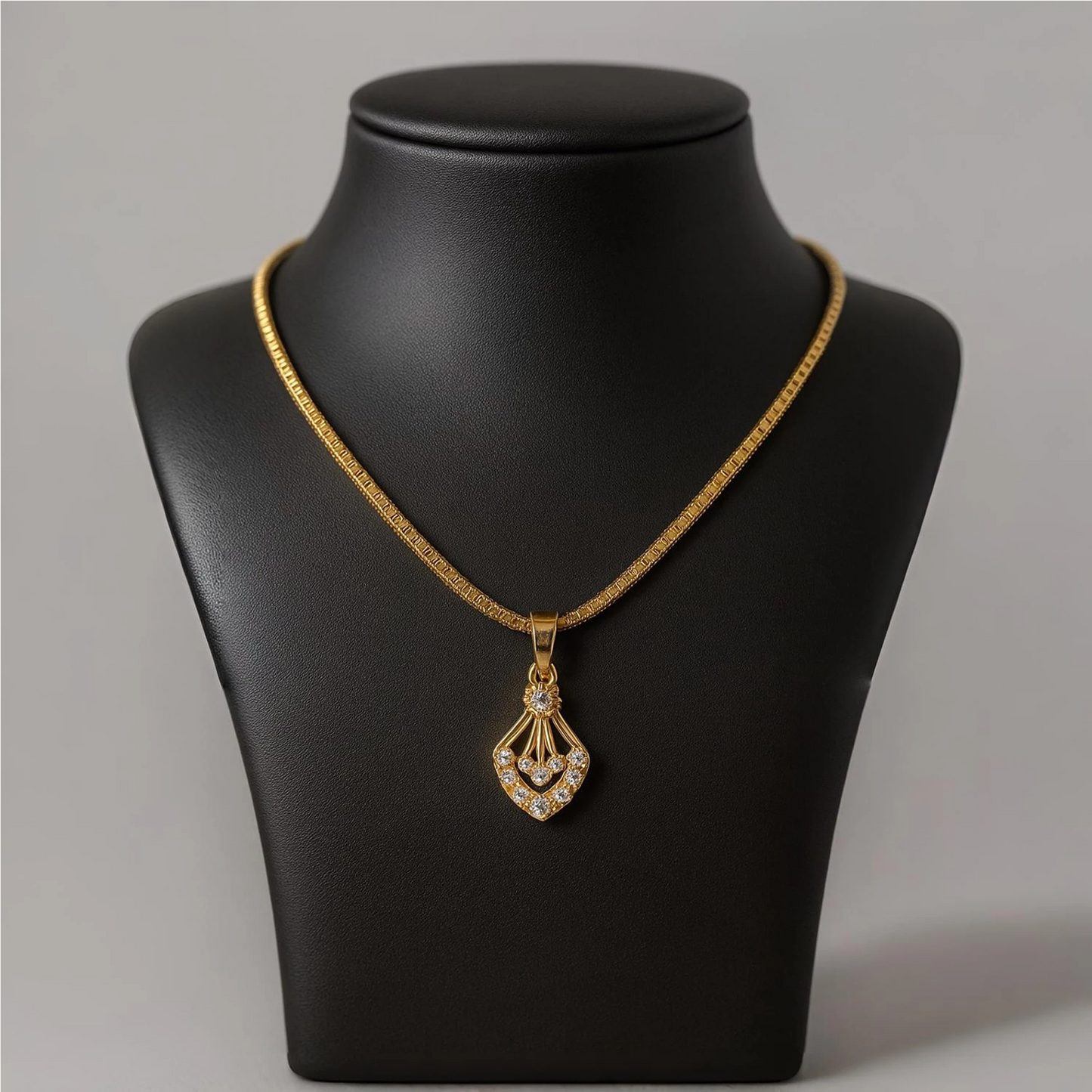 Gold necklace with a pendant on a black mannequin bust against a gray background