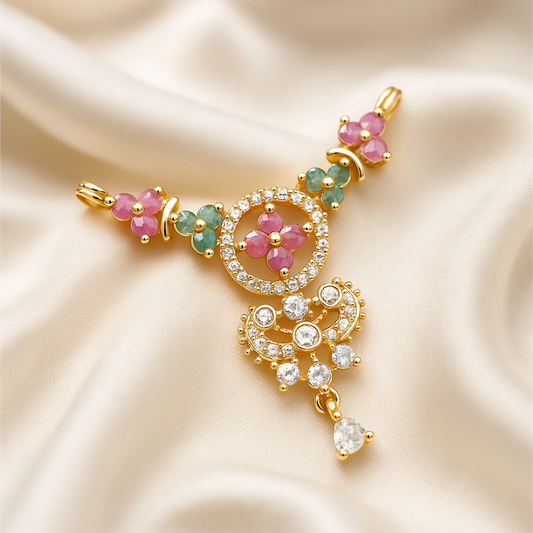 Gold pendant with pink and green gemstones on a beige satin background