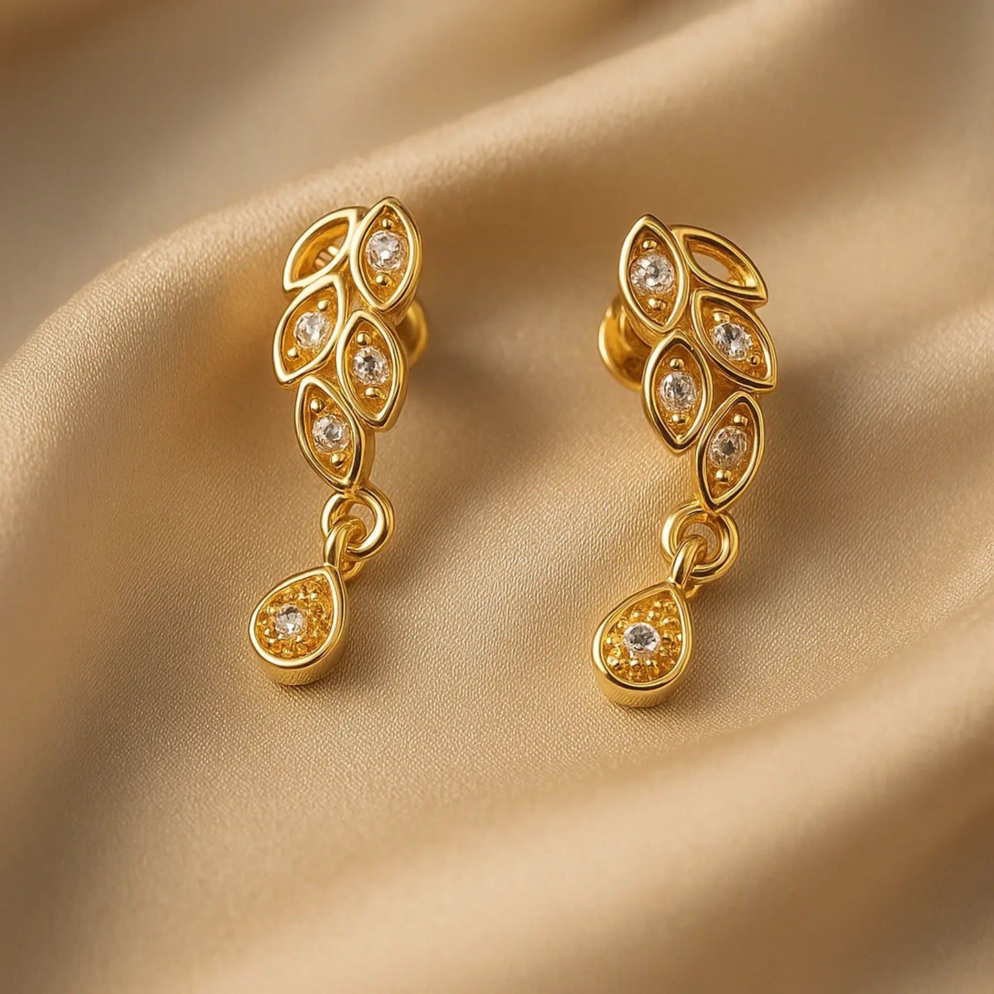 Gold earrings with diamond accents on a beige fabric background