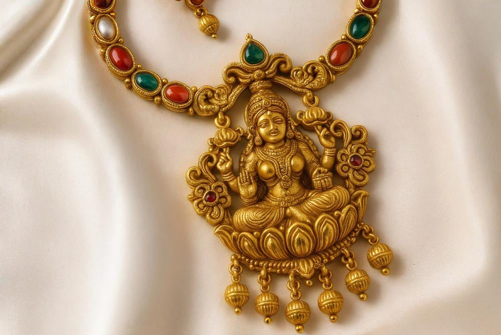 Gold necklace with a deity pendant on a white background