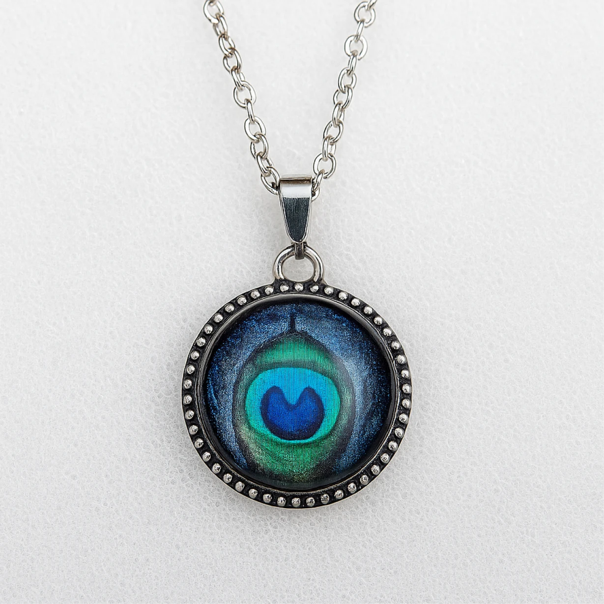 Necklace with a round pendant featuring a blue and green design on a light gray background