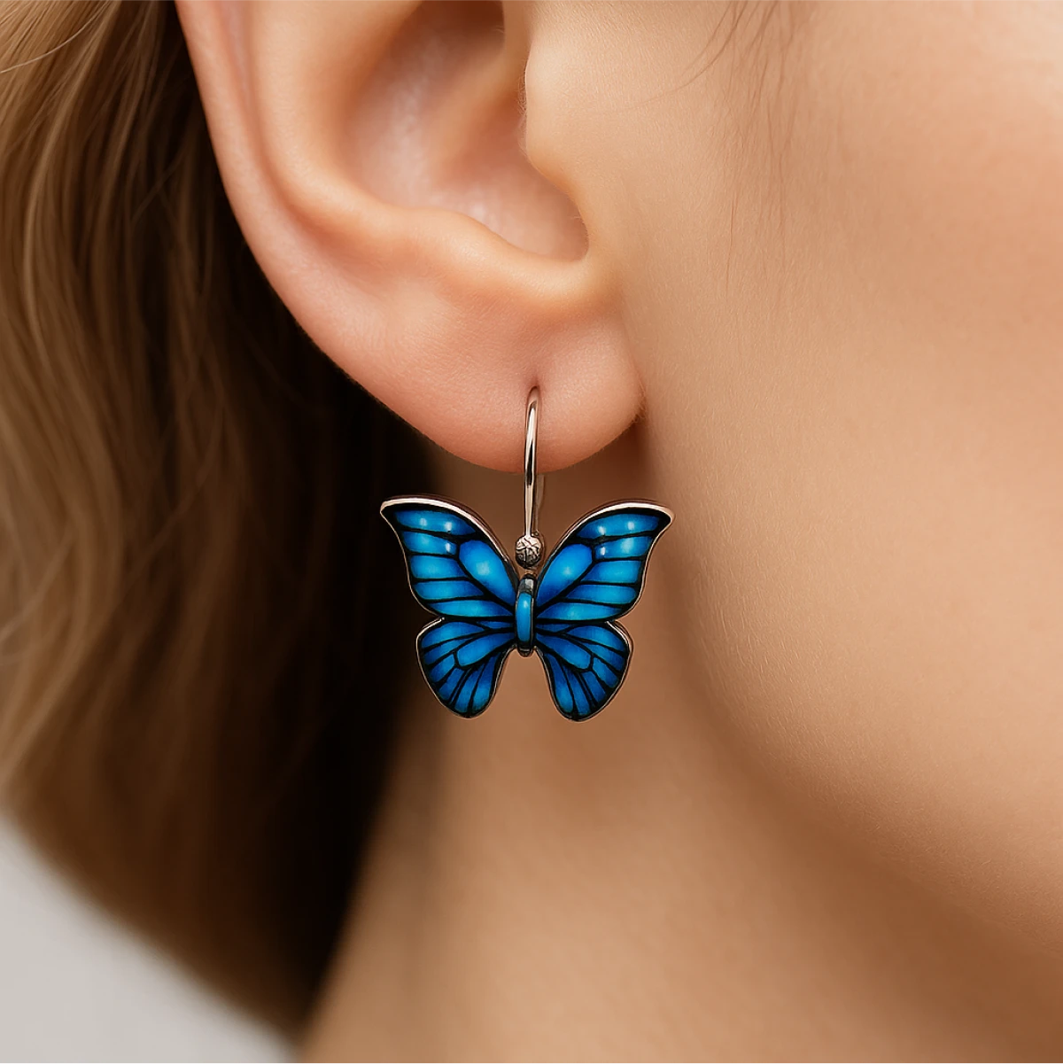 Blue butterfly earring worn on an ear with a neutral background
