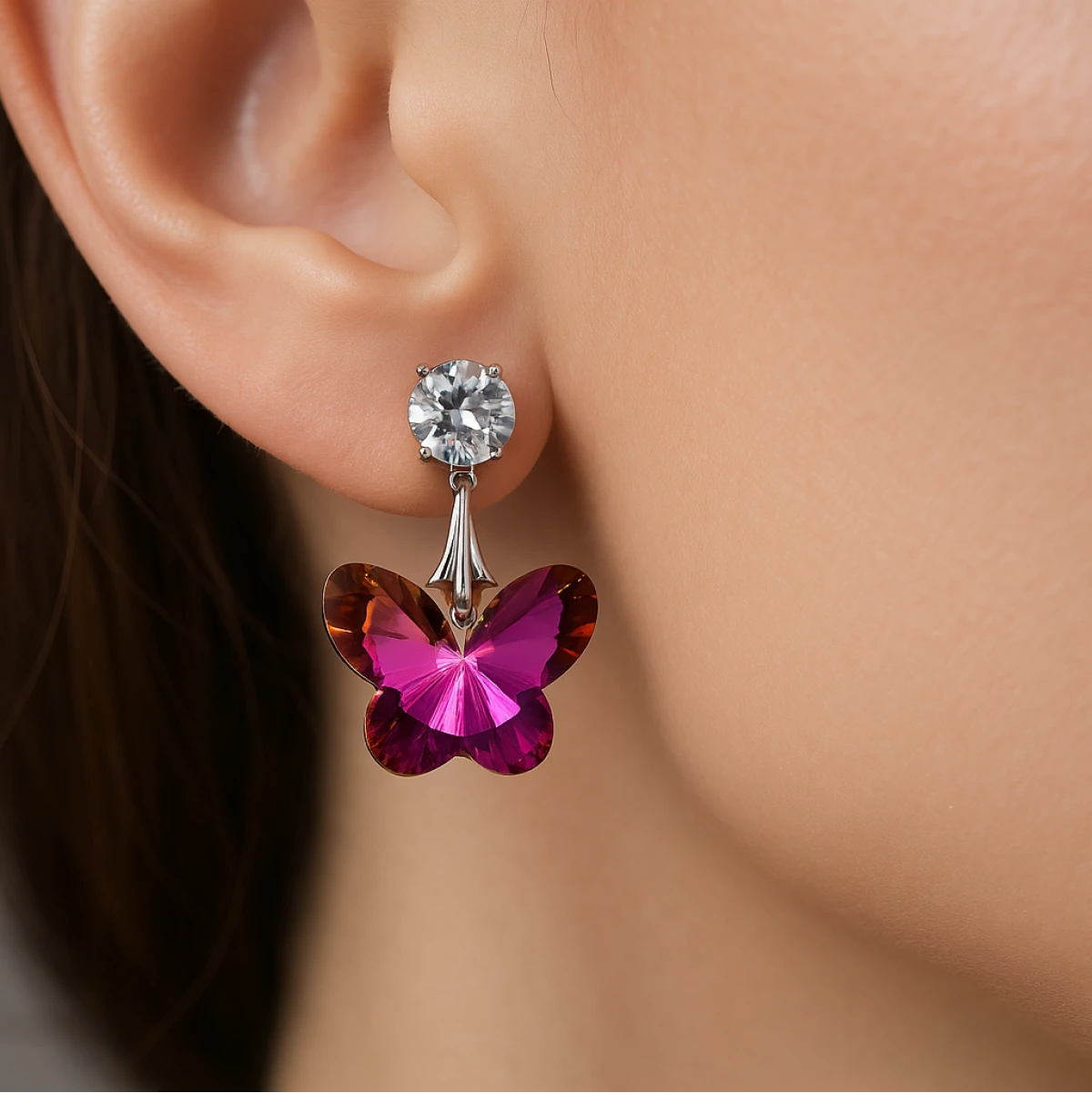 Butterfly-shaped earring with pink and brown wings worn on an ear