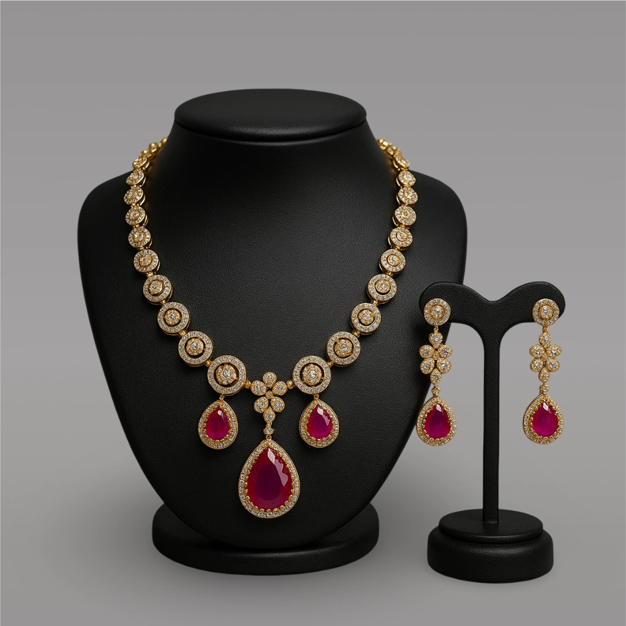 Gold necklace with red gemstones and matching earrings on a black stand against a gray background