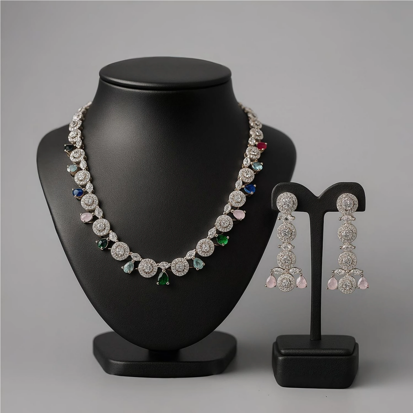 Jewelry set with necklace and earrings on black stands against a gray background