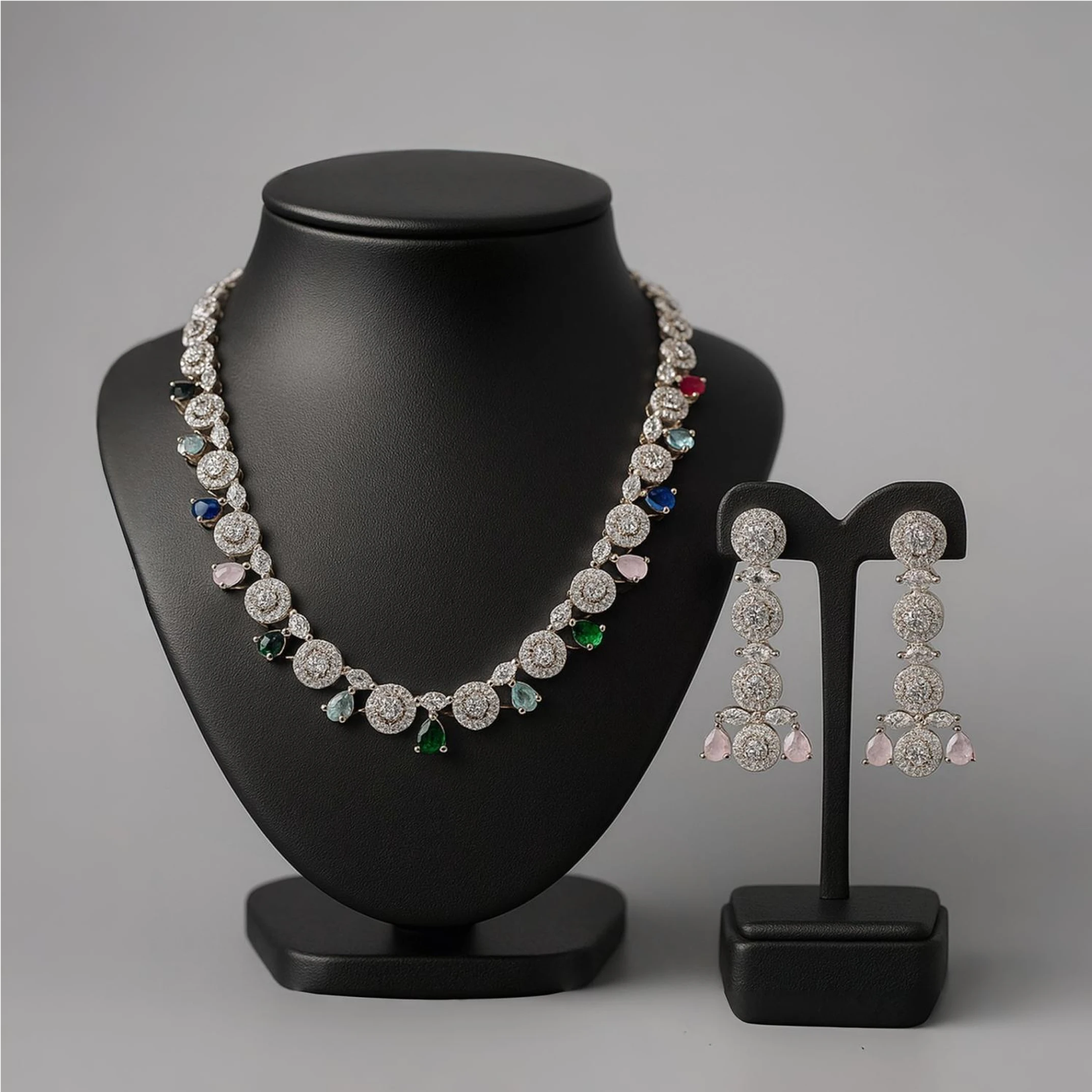 Jewelry set with necklace and earrings on black stands against a gray background