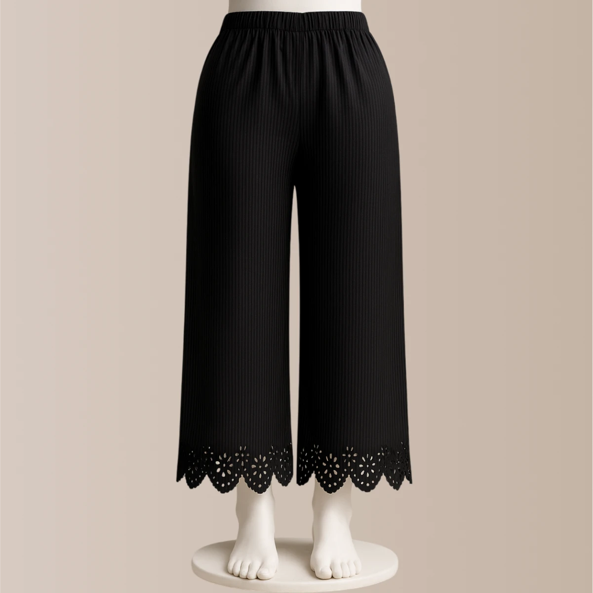 Black pants with lace trim on a beige background