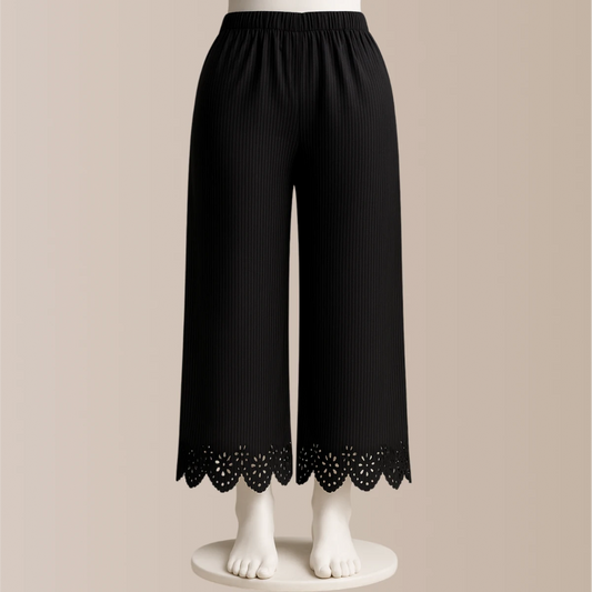 Black pants with lace trim on a beige background