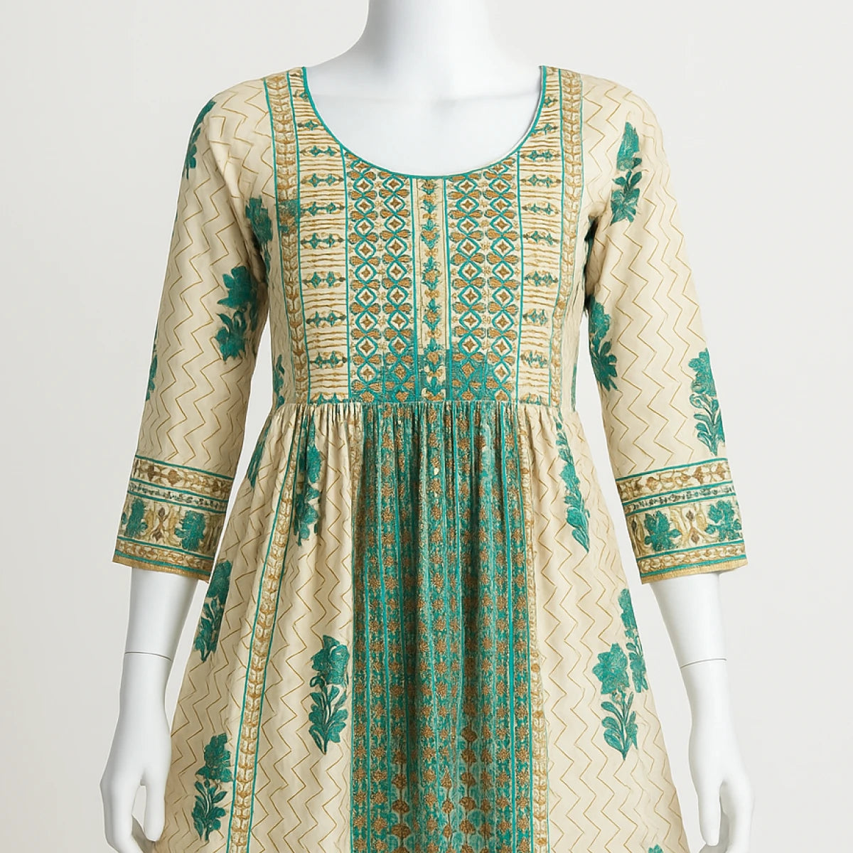 Beige dress with green patterns on a mannequin against a white background